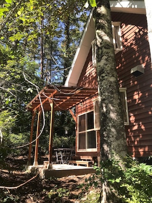 A wooden cabin with a covered porch, a window, and a small outdoor seating area. - Paseo Resort Club (Fujikawaguchiko)
