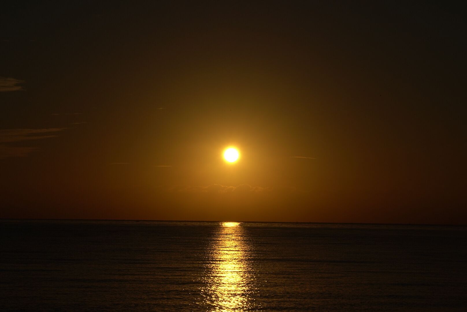 A sunset over the ocean with a clear sky.