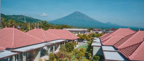 A resort with red-roofed buildings, a central courtyard, and a mountain in the background.