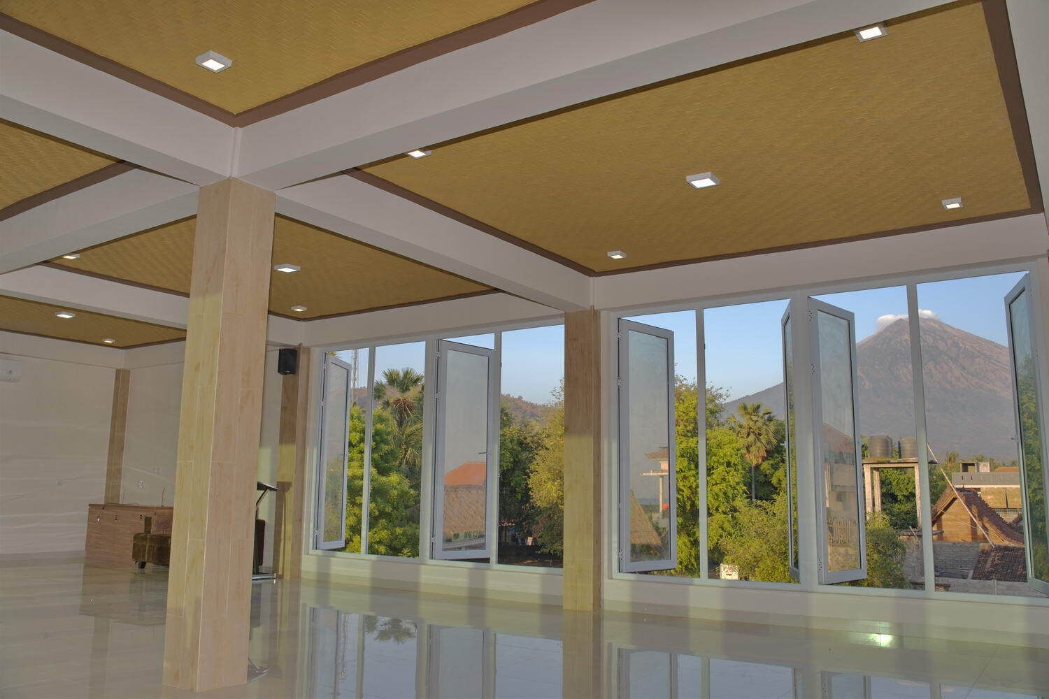 A spacious room with large windows, a polished floor, and a high ceiling with recessed lighting.
