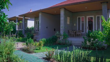 Una casa de dos pisos con un porche cubierto, un pequeño jardín y un patio con mobiliario exterior.