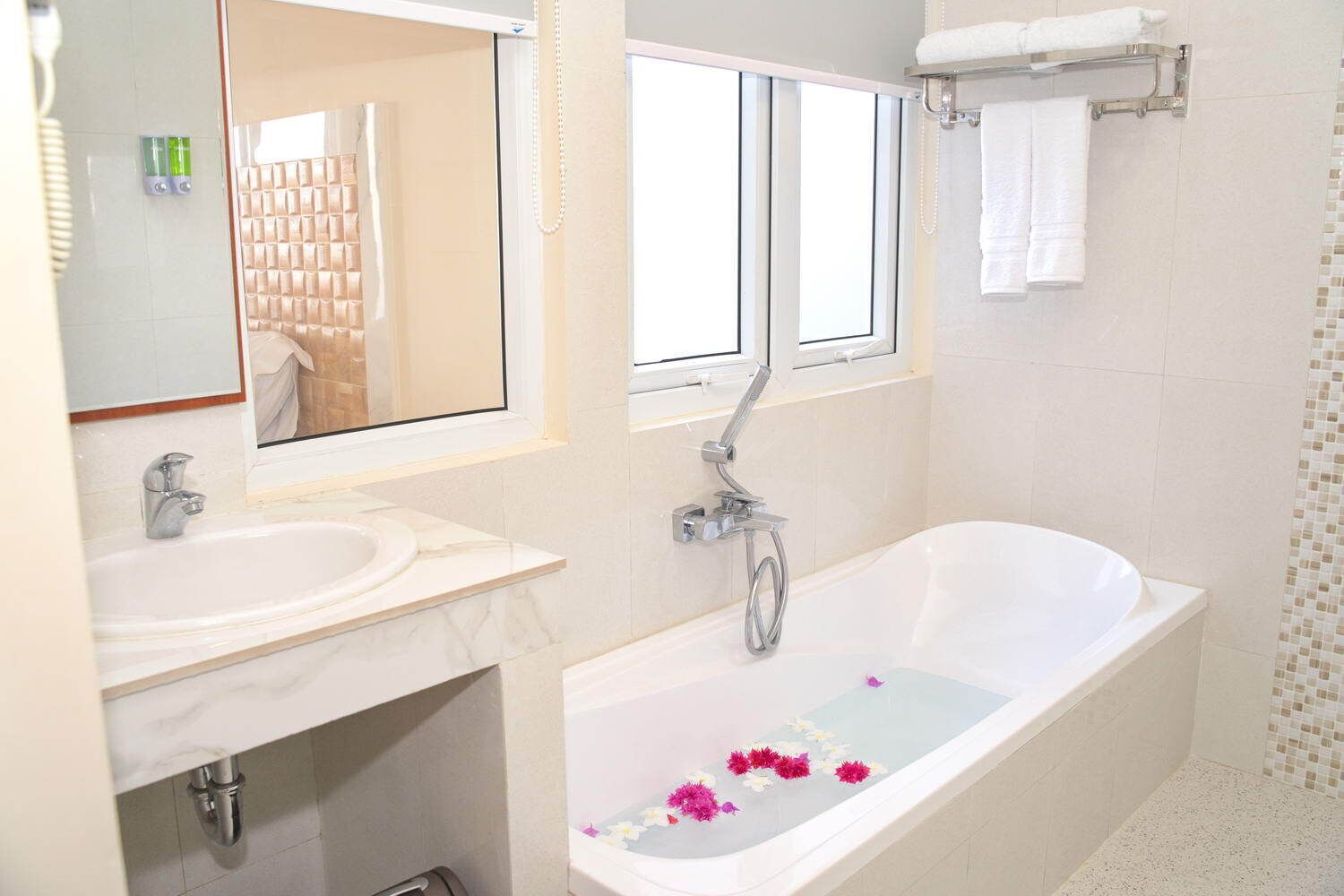 A modern bathroom with a bathtub, two sinks, and a large mirror.