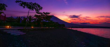 A beach at sunset with a mountain in the background.