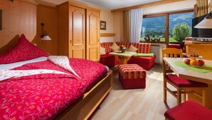 Ein gemütliches Zimmer mit einem Bett, einem kleinen Tisch, einer Couch und Blick ins Freie.