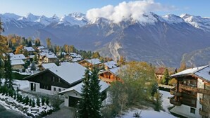 Un poble de muntanya amb cases cobertes de neu i una vista de cims nevats.
