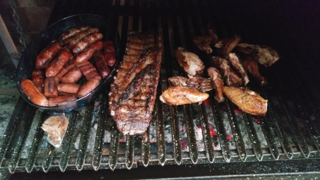 A grill with various meats, including sausages, steaks, and chicken.