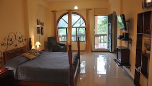 A bedroom with a bed, a chair, a TV, and a balcony with curtains. - Mountain Lodge CheTica (San Jeronimo)