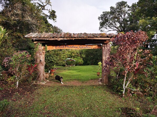 A garden entrance with a wooden archway and a banner reading "Enlat Meadow Garden".