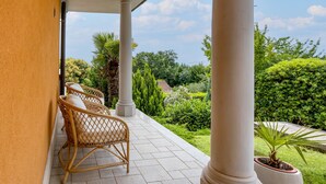 A covered outdoor seating area with wicker chairs and a potted plant. - Awesome home in Opric (Opric)