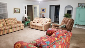 A living room with striped sofas, a floral sofa, a brown leather armchair, and a green table. - Lazy Daze! Pups OK, Ideal location! Fenced Yard, Nice House. Wonderful! (Gulf Shores)