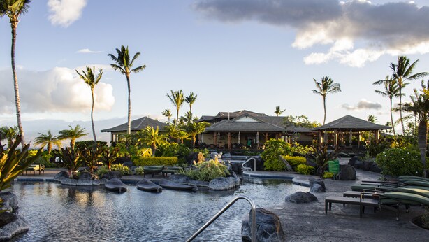 A resort with a swimming pool, palm trees, and a gazebo.