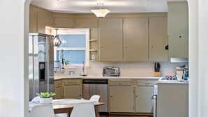 A modern kitchen with a dining area, stainless steel appliances, and light-colored cabinetry.