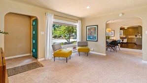 A spacious living area with a view to the outdoors, a dining area, and a kitchen visible through an archway.