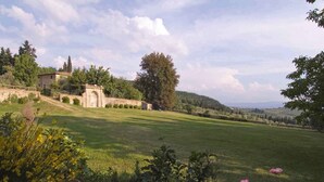 A rural landscape with a stone archway, a grassy field, and a building in the background. - Holiday home Two-room apartment for 2 (Pelago)