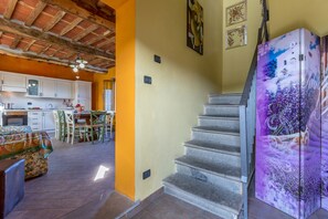A kitchen with white cabinets, a dining table with chairs, and a staircase with a decorative refrigerator. - Casale Geniva with private pool, Massarosa, Italy (Massarosa)