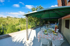 A covered outdoor dining area with a table set for four, surrounded by white chairs, under a green canopy. - Casale Geniva with private pool, Massarosa, Italy (Massarosa)