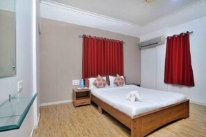 Ein Schlafzimmer mit einem hölzernen Bett, roten Vorhängen, einer Duschkabine aus Glas und einer weißen Wand mit Klimaanlage.
