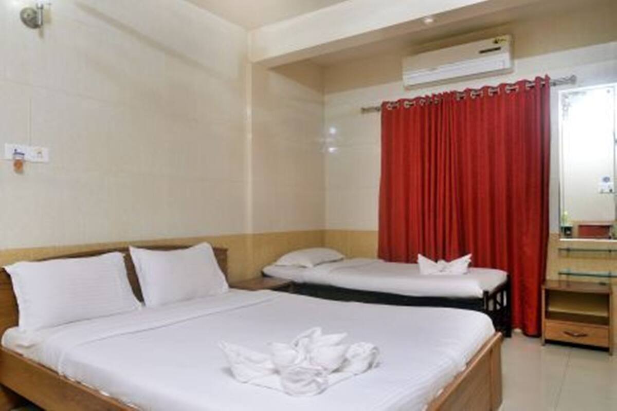 Ein Hotelzimmer mit zwei Betten, einem roten Vorhang und einer Klimaanlage.