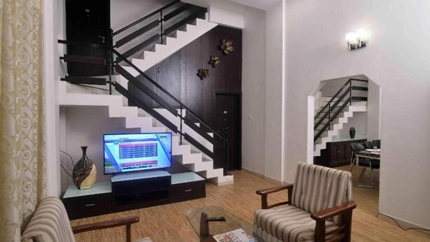 Un salon avec un escalier, un téléviseur à écran plat et un coin repas.