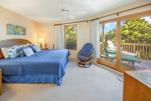 Un dormitorio con una cama grande, una silla, un escritorio y vistas al exterior.