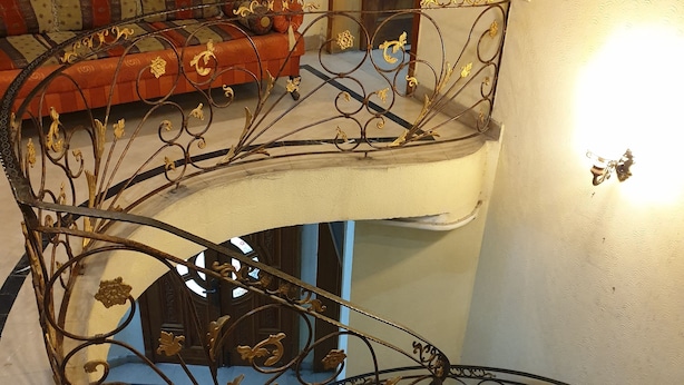 A staircase with ornate metal railings and a cushioned bench at the top. - Chinese Guest House (Lahore)