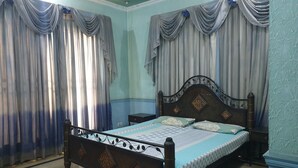 A bedroom with a wooden bed, two nightstands, and curtains. - Chinese Guest House (Lahore)