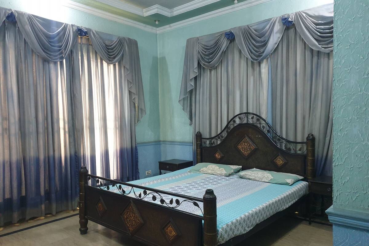 A bedroom with a wooden bed, two nightstands, and curtains.