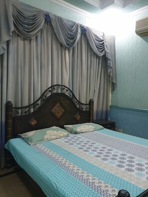 A room with a bed, a small table, and curtains. - Chinese Guest House (Lahore)
