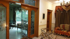 A spacious living area with a glass partition, a red sofa, and a chandelier. - Chinese Guest House (Lahore)