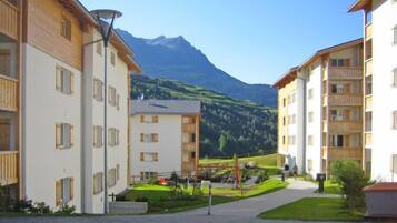 Un quartier résidentiel avec des immeubles modernes, une aire de jeux et une montagne en arrière-plan.
