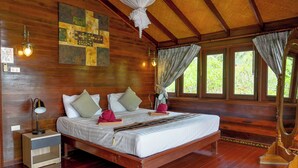 A wooden bedroom with a bed, bedside lamps, and a window with curtains. - Thai Style Wooden Beachfront Villa with Private Sala (Koh Samui)