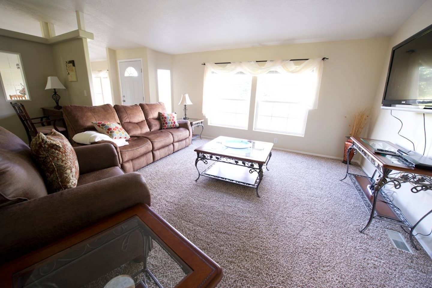 A living room with a brown sofa, a glass coffee table, and a television.