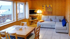 L’intérieur d’un chalet accueillant, avec une table à manger, des chaises, un canapé et un téléviseur.