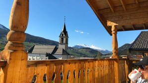 Un balcon en bois offrant une vue sur une église et des montagnes.