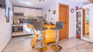Une cuisine moderne avec un îlot central en bois, deux tabourets de bar et une table à manger.