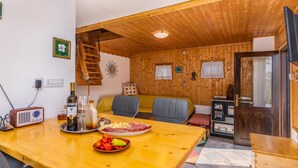 Un intérieur en bois avec une table à manger dressée pour le repas, une radio et un plafond en bois.