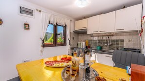 Une cuisine avec une table à manger dressée pour un repas, comprenant une bouteille de vin, des verres et un plateau avec de la nourriture et des boissons.