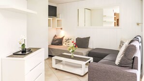 A modern living room with a sofa, a coffee table, a TV, and a small side table with a vase of flowers. - Mont-Fort 64 by Interhome (Siviez-Nendaz)