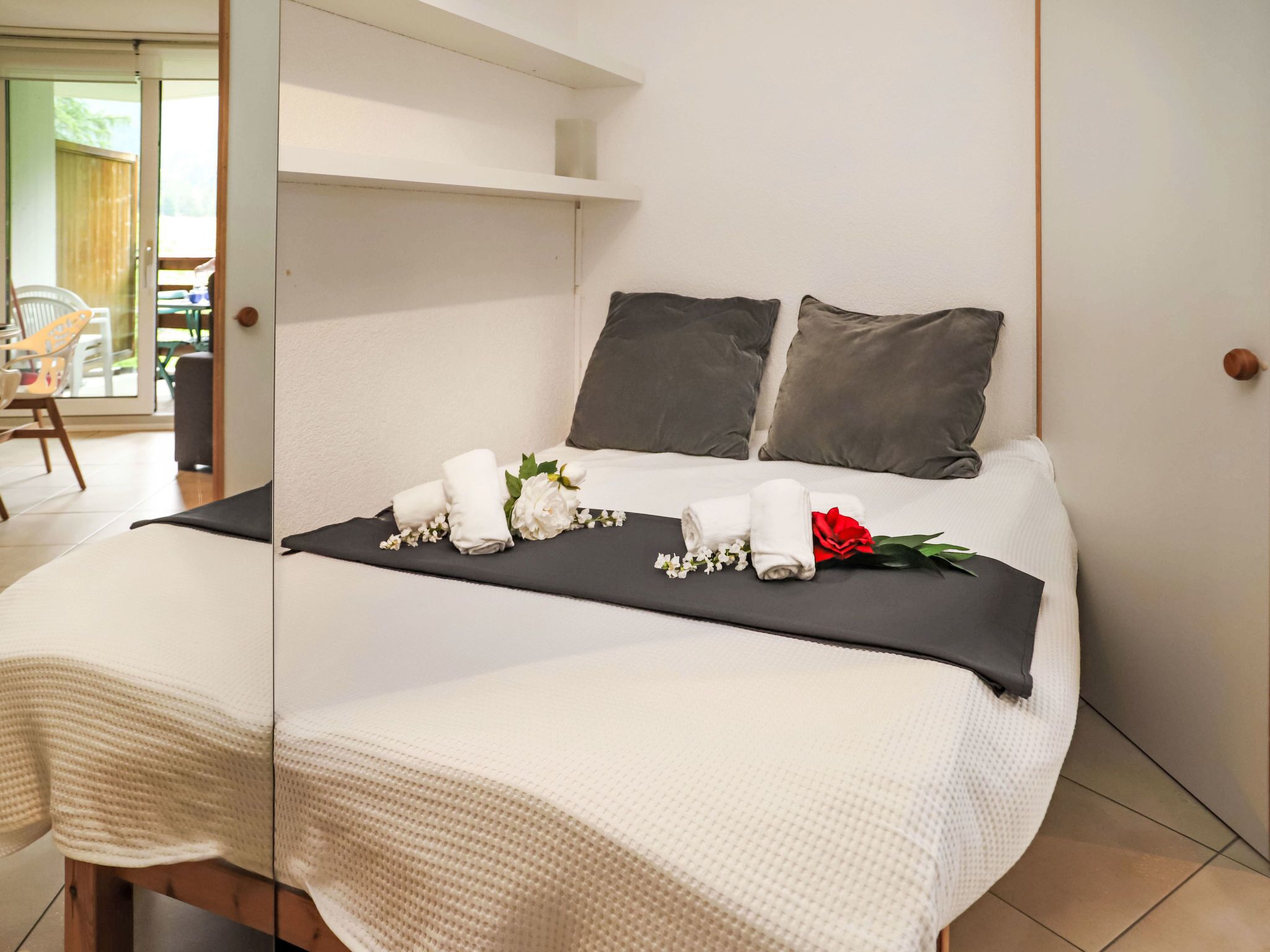Una cama bien hecha con sábanas blancas, dos almohadas oscuras y una colcha negra.