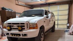 Een witte pick-up truck geparkeerd in een garage met een betonnen vloer en een metalen garagedeur.