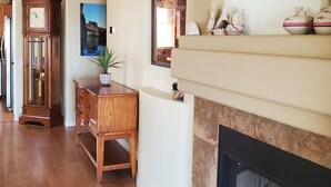 Ein Wohnzimmer mit Kamin, einer Uhr, einem Holztisch und einem großen Spiegel.