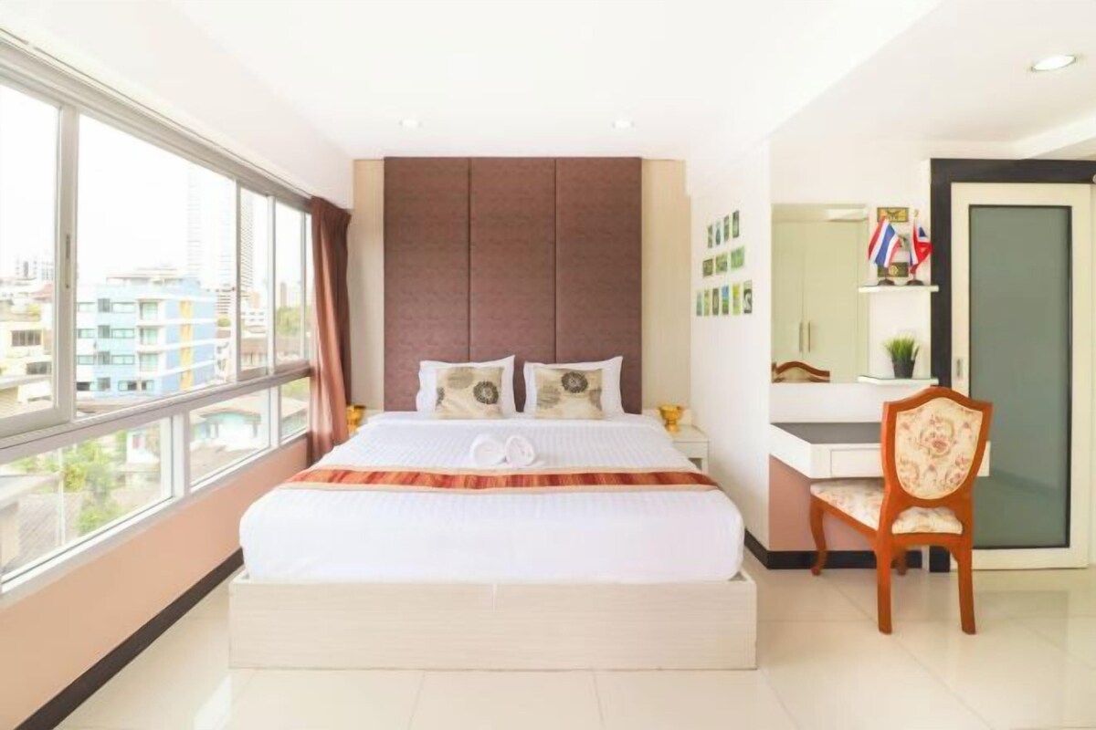 A hotel room with a large bed, a desk, and a chair.