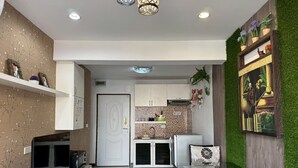Eine moderne Küche mit weißen Schränken, einer gefliesten Spritzschutzwand und einem Essbereich mit einem Glastisch und Korbstühlen.