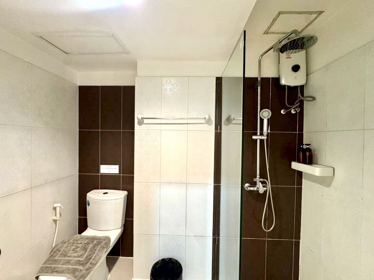 Et badeværelse med toilet, bruser og et håndklædestativ.