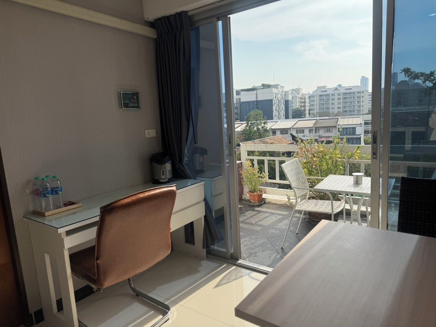 Habitación de hotel con escritorio, silla y balcón con mesa y sillas.