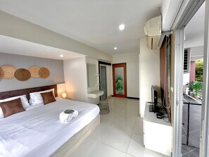 Ein Hotelzimmer mit Bett, Schreibtisch, Fernseher und einer Tür zu einem Balkon.