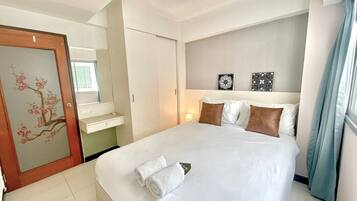 A hotel room with a large bed, a bedside table, a mirror, and a door with floral artwork.