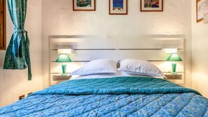 Um quarto com uma cama, duas luminárias de cabeceira e três quadros na parede.