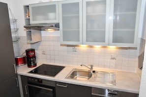 A modern kitchen with a built-in oven, a stovetop, a sink, and a coffee maker.