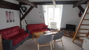 A cozy living room with a red sofa, a wooden table, and a TV. - sparrow's nest - vikingerhof (Wittmund)